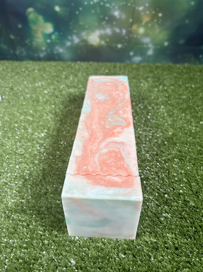 Long rectangular block with orange and green marbled pattern on a green grass-like background