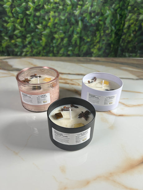 Three candles on a marble surface with a green leafy background