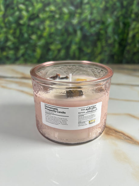 Candle in a large pink glass container with a label 