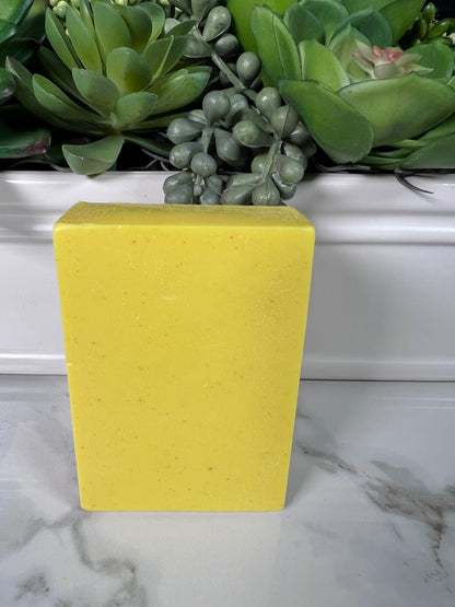 Rectangular bar of yellow turmeric soap on a marble surface.