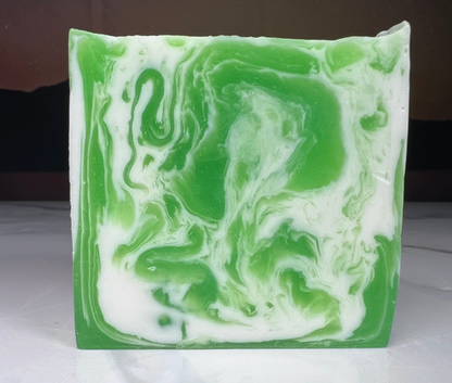 Large green and white swirled square-like soap bar on a white surface with a dark background